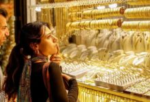 सोने के सिक्के और बिस्कुट के साथ ऊपर की ओर बढ़ता हुआ शेयर बाजार का एक डिजिटल हरा तीर