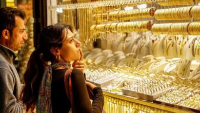 सोने के सिक्के और बिस्कुट के साथ ऊपर की ओर बढ़ता हुआ शेयर बाजार का एक डिजिटल हरा तीर