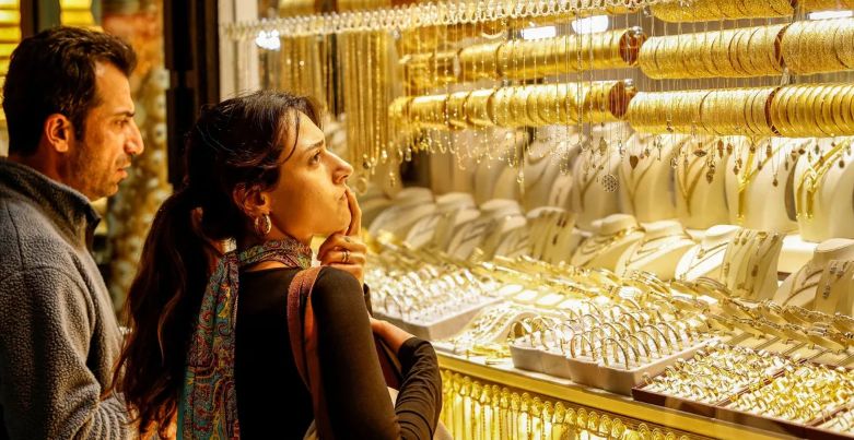 सोने के सिक्के और बिस्कुट के साथ ऊपर की ओर बढ़ता हुआ शेयर बाजार का एक डिजिटल हरा तीर