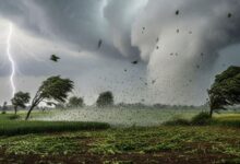 A conceptual image showing dark stormy clouds, heavy rain, and lightning over a city landscape, highlighting the IMD weather alert for 80kmph winds and hail in India.