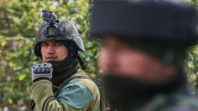 भारतीय सेना के जवान इलेक्ट्रिक वाहन के पास खड़े हुए और बैकग्राउंड में सोलर पैनल का प्रतीकात्मक चित्र