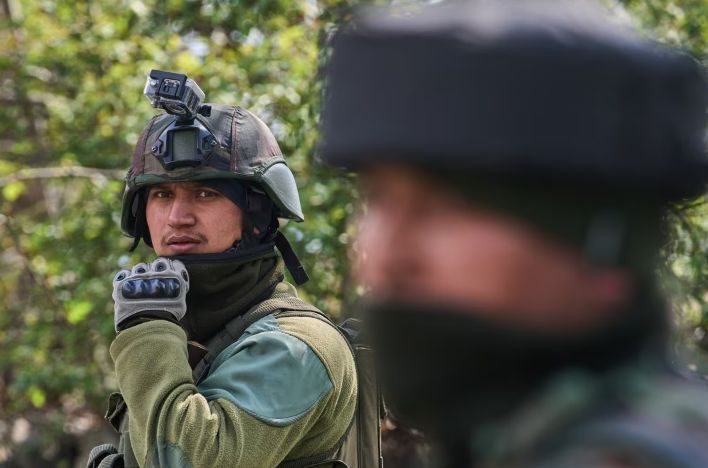 भारतीय सेना के जवान इलेक्ट्रिक वाहन के पास खड़े हुए और बैकग्राउंड में सोलर पैनल का प्रतीकात्मक चित्र