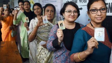 चुनाव प्रचार के दौरान हाथ जोड़े हुए ग्रामीण भारतीय महिलाओं का समूह और पीछे राजनीतिक रैलियों का दृश्य